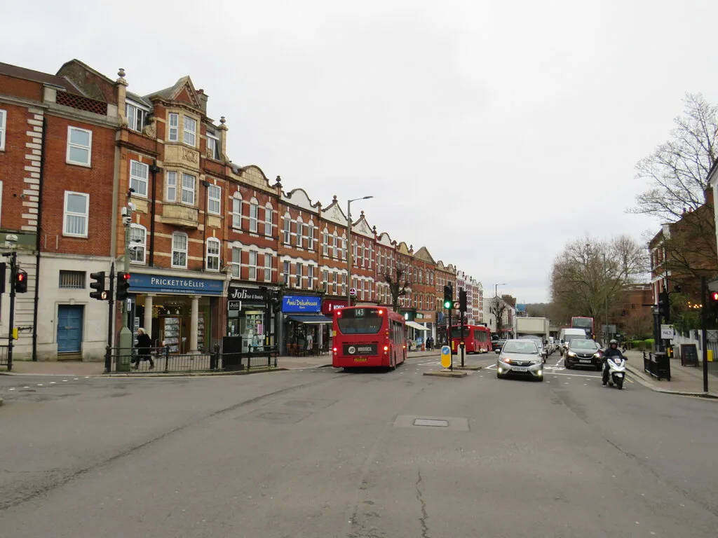 The parade of shops on the High Road in East Finchley, with a bus at the lights