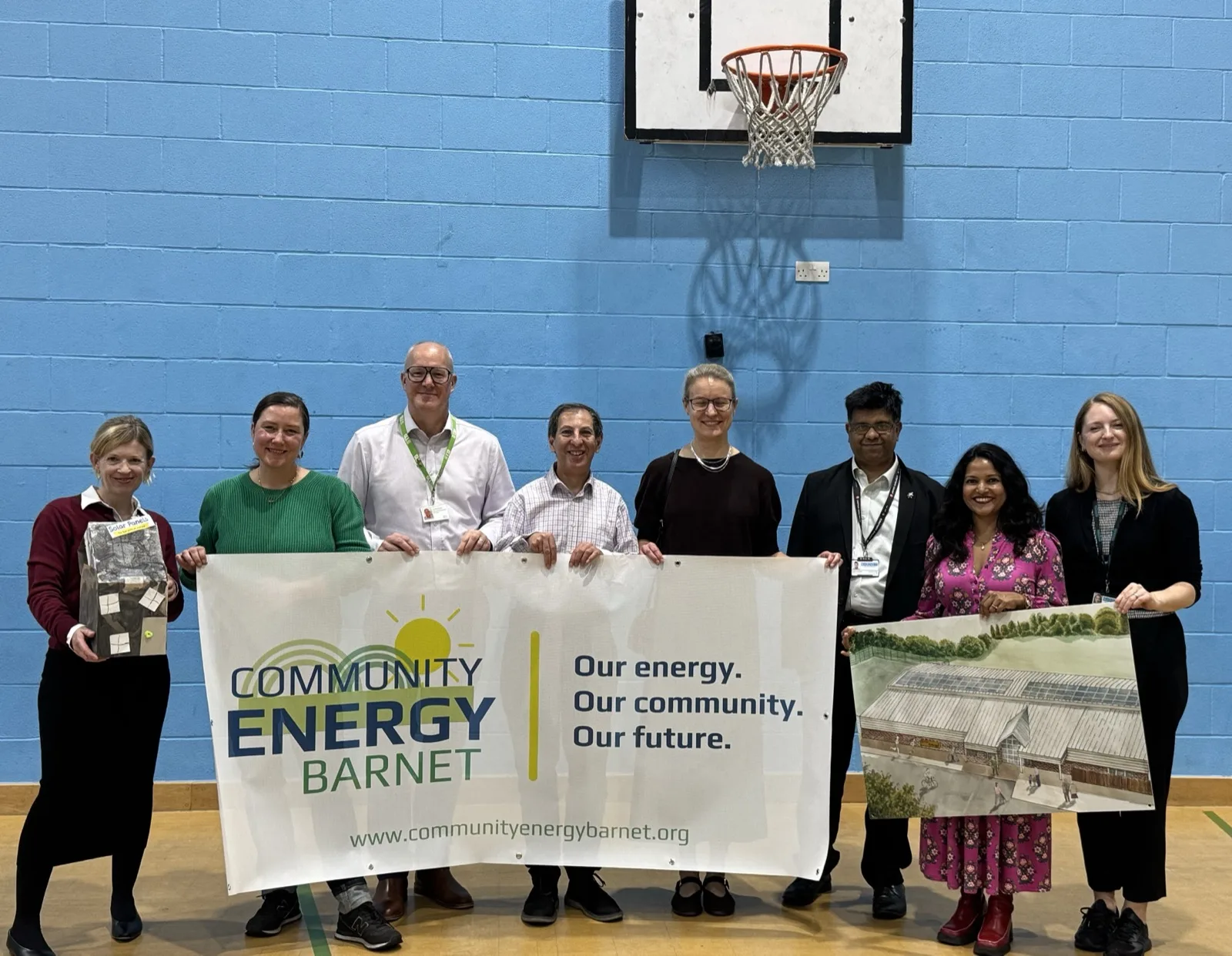 Community Energy Barnet volunteers and project partners in the sports hall at Burnt Oak Leisure Centre, with a drawing of the solar roof on the right
