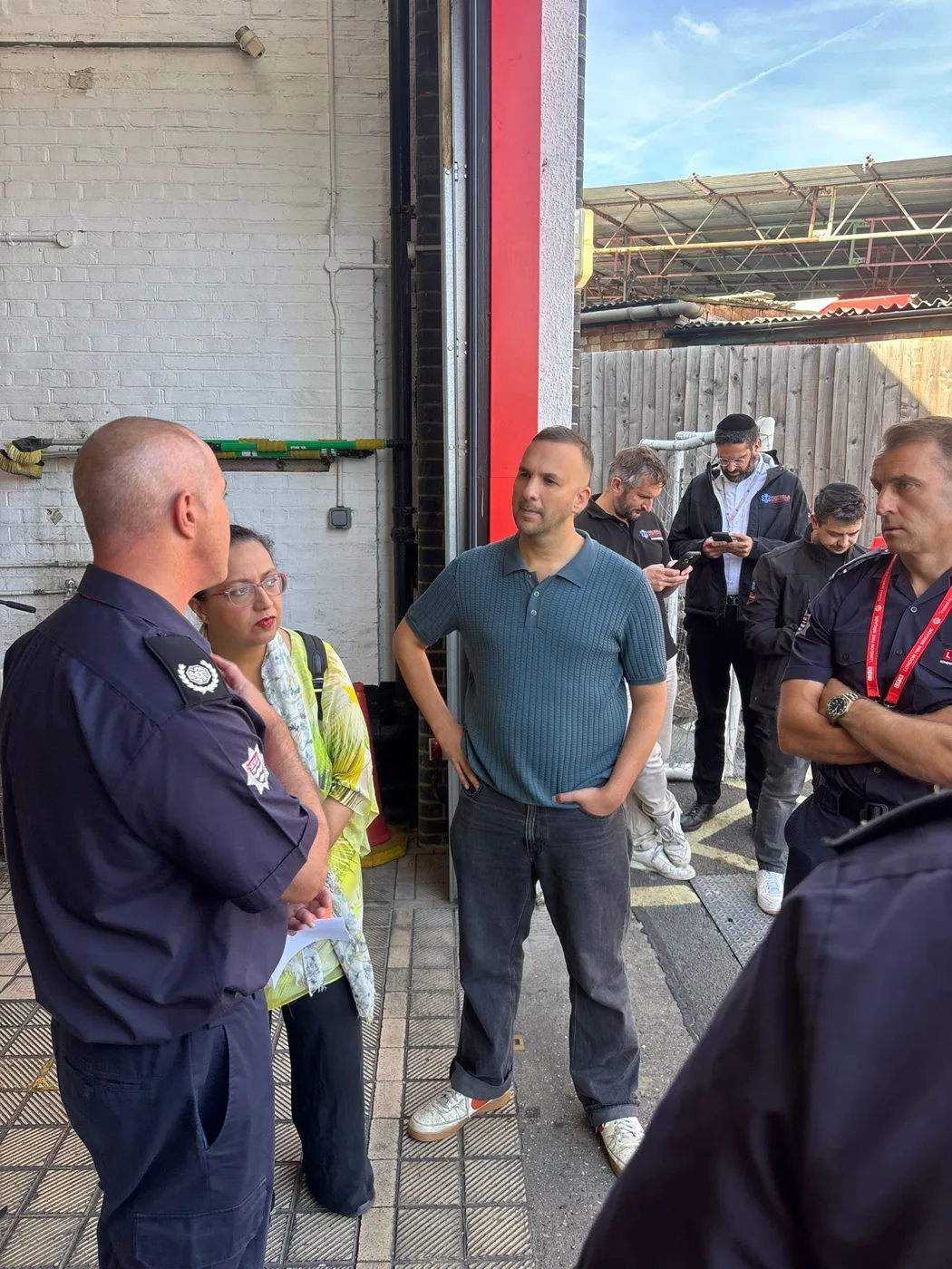 Firefighters talking with visitors in the appliance bay at Finchley Road Fire Station